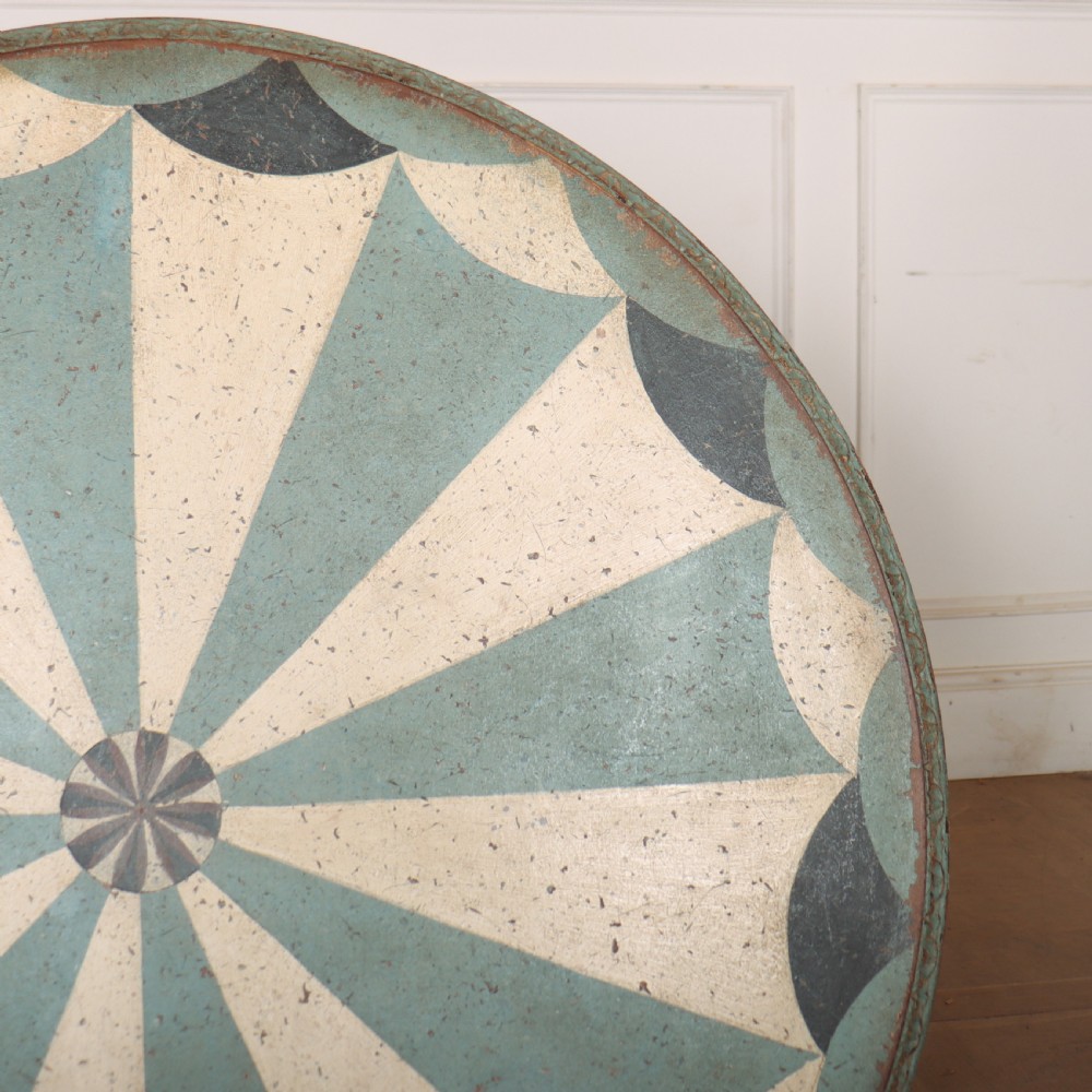 A round blue painted lamp table featuring a starburst pattern top, carved scroll legs, and an X-frame base. View XI