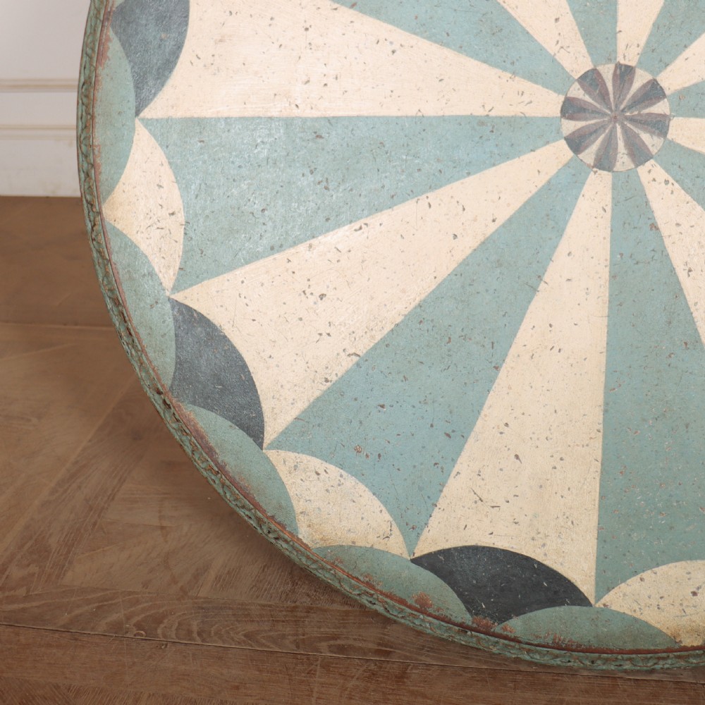 A round blue painted lamp table featuring a starburst pattern top, carved scroll legs, and an X-frame base. View XII