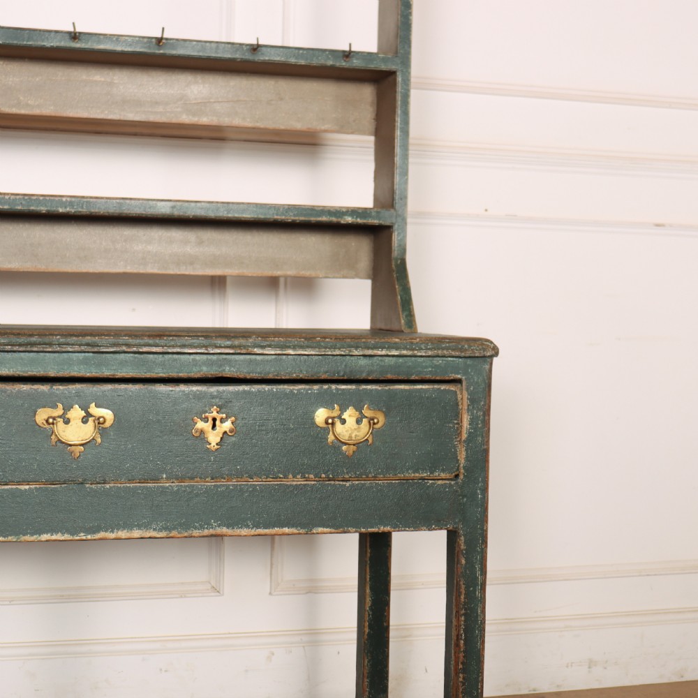 An antique dark green painted wooden pot board dresser featuring an upper three-tier plate rack with cup hooks above two drawers and an open bottom shelf. View IV