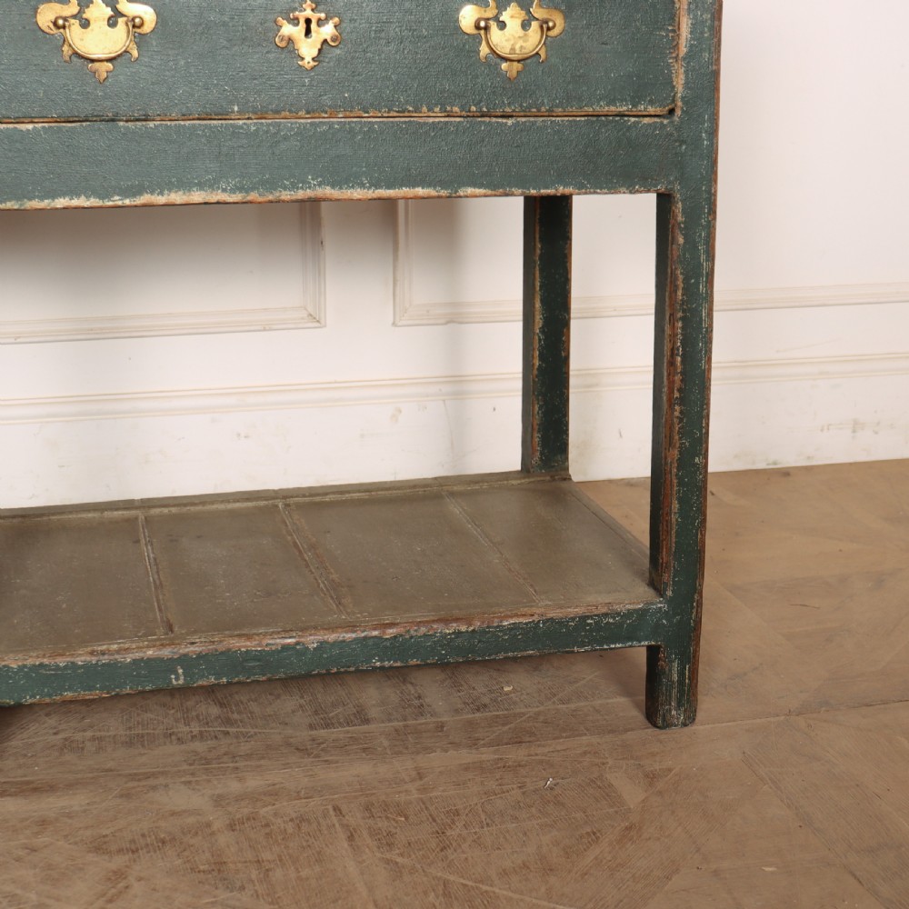 An antique dark green painted wooden pot board dresser featuring an upper three-tier plate rack with cup hooks above two drawers and an open bottom shelf. View V