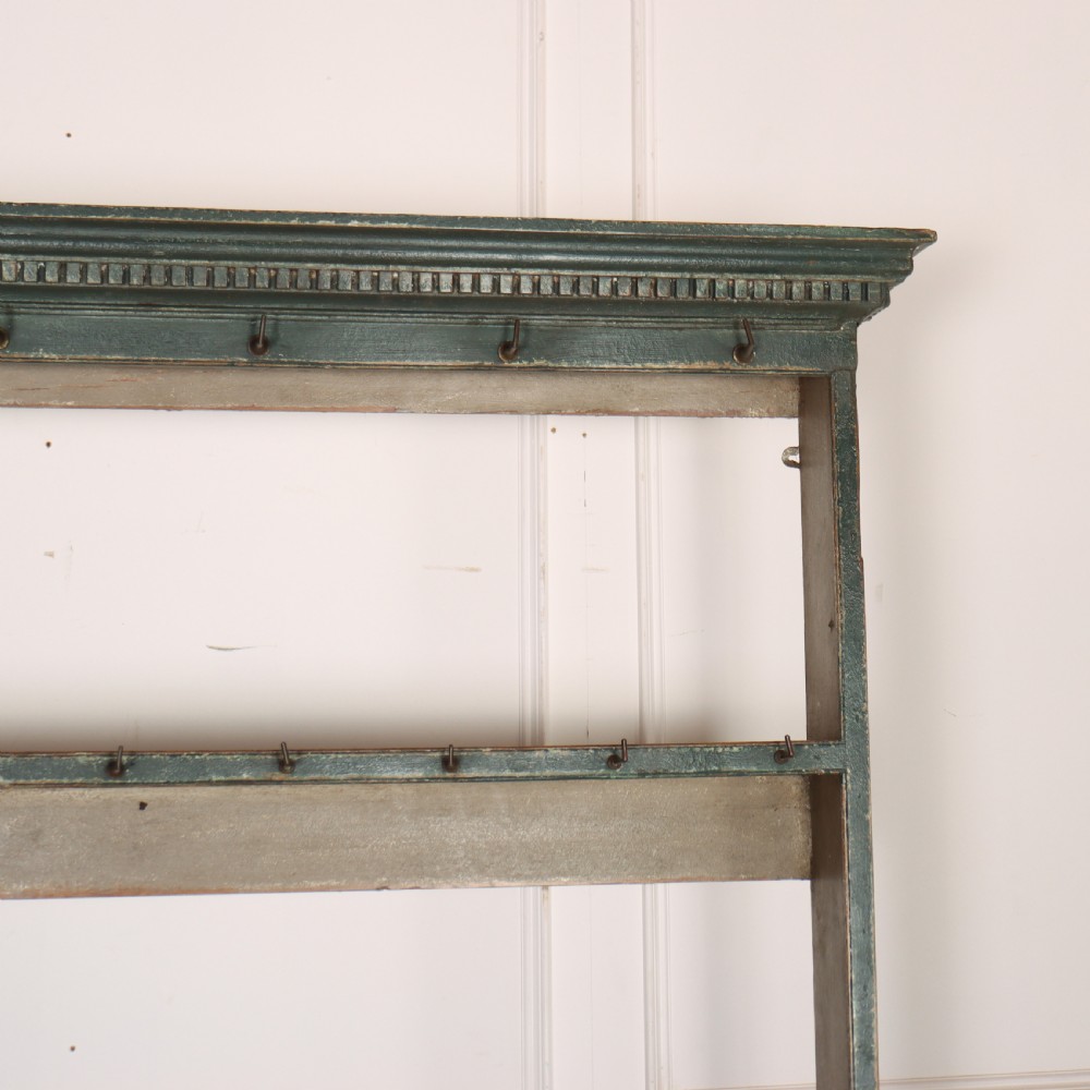 An antique dark green painted wooden pot board dresser featuring an upper three-tier plate rack with cup hooks above two drawers and an open bottom shelf. View VI