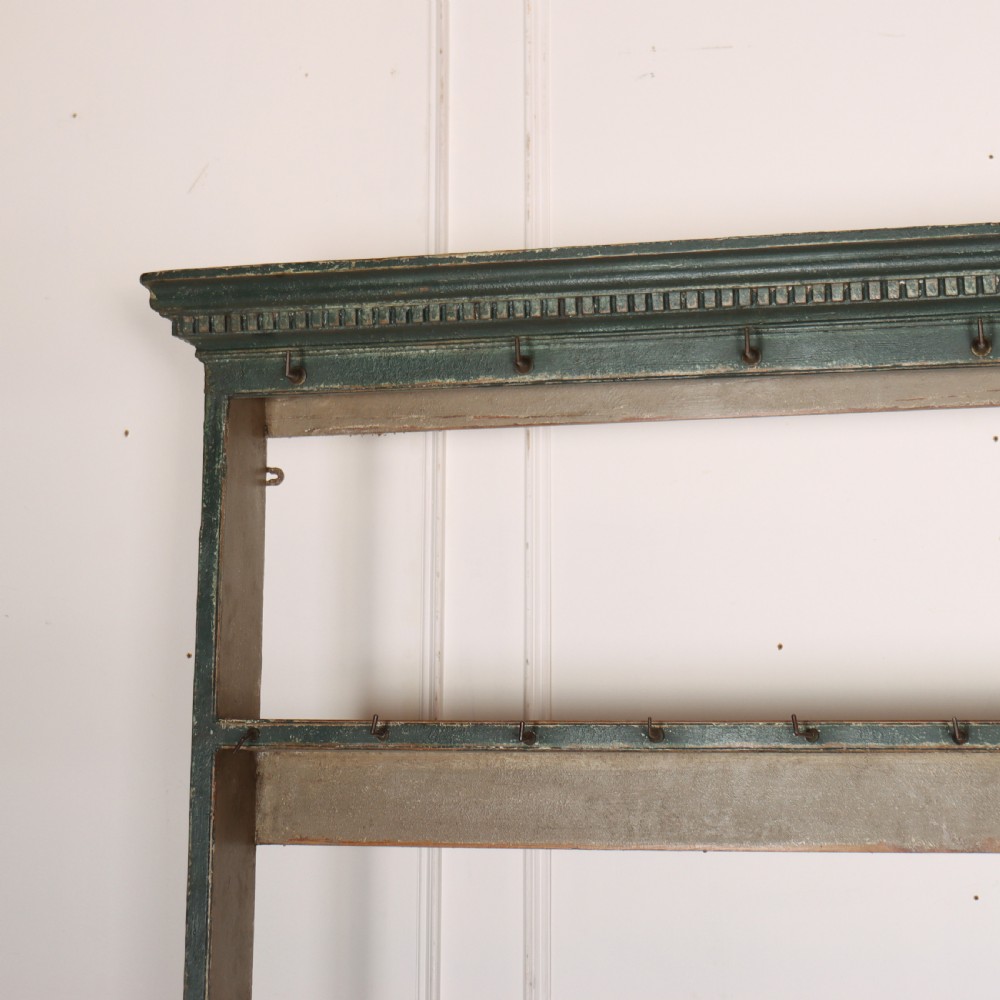 An antique dark green painted wooden pot board dresser featuring an upper three-tier plate rack with cup hooks above two drawers and an open bottom shelf. View VII