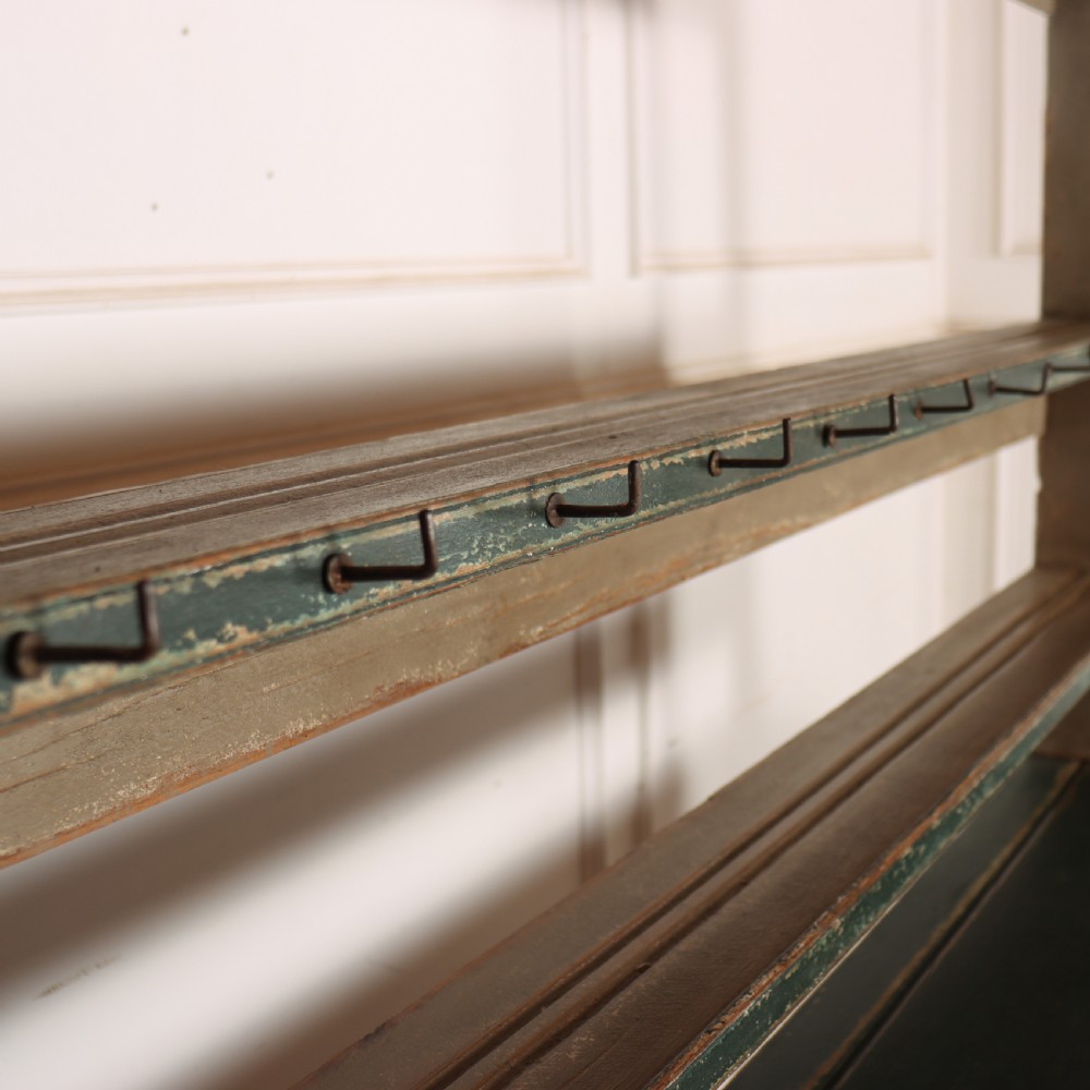 An antique dark green painted wooden pot board dresser featuring an upper three-tier plate rack with cup hooks above two drawers and an open bottom shelf. View VIII