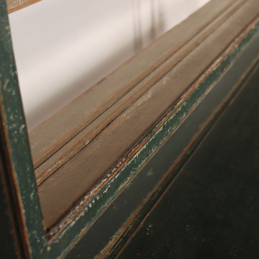 An antique dark green painted wooden pot board dresser featuring an upper three-tier plate rack with cup hooks above two drawers and an open bottom shelf. View IX