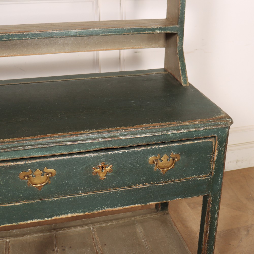 An antique dark green painted wooden pot board dresser featuring an upper three-tier plate rack with cup hooks above two drawers and an open bottom shelf. View XI
