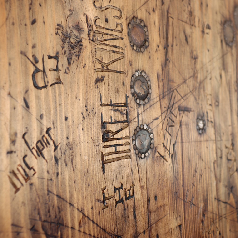 A low rectangular wooden coffee table featuring turned reeded legs and a surface decorated with carved typography and circular details. View XII
