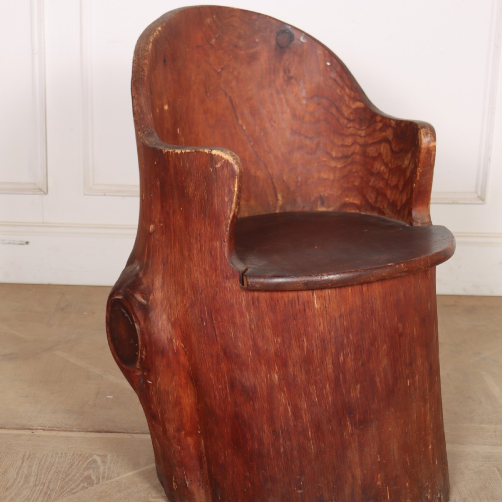 A Swedish dugout armchair carved from a single hollowed-out wooden tree trunk showing natural grain, knots, and a rounded seat. View II