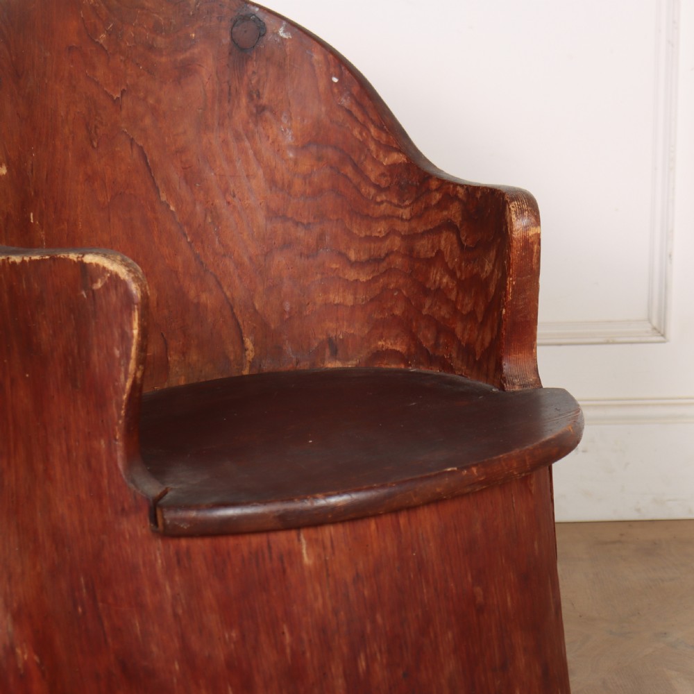 A Swedish dugout armchair carved from a single hollowed-out wooden tree trunk showing natural grain, knots, and a rounded seat. View III