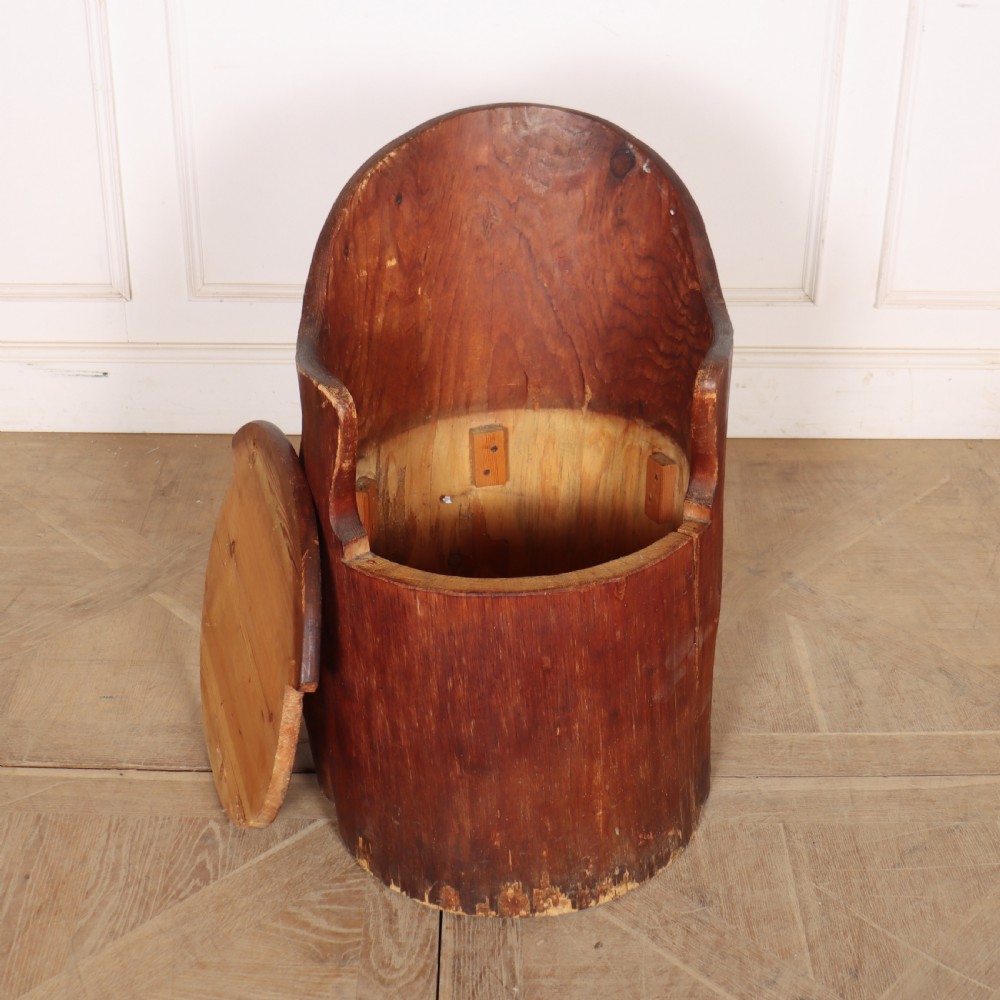 A Swedish dugout armchair carved from a single hollowed-out wooden tree trunk showing natural grain, knots, and a rounded seat. View IV