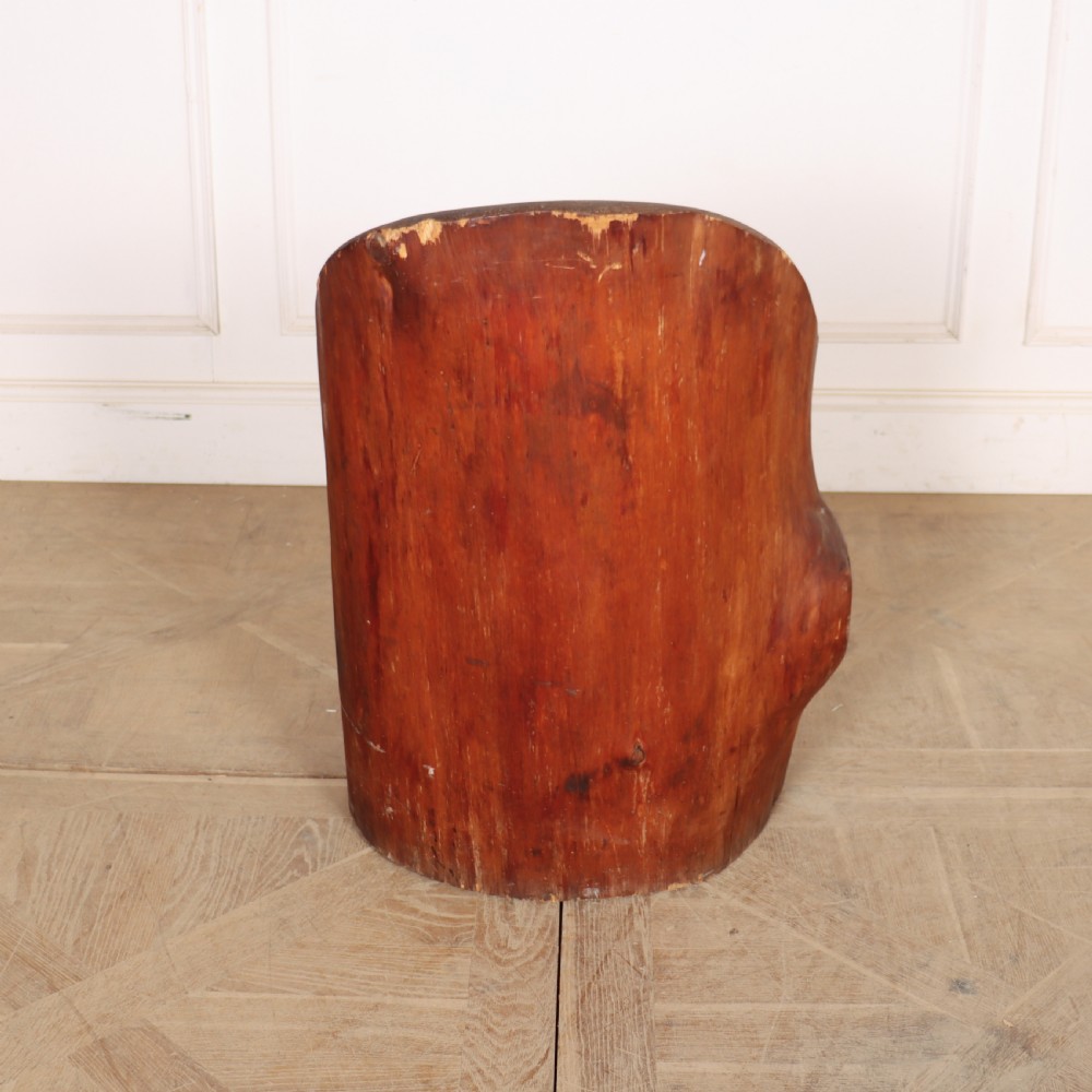 A Swedish dugout armchair carved from a single hollowed-out wooden tree trunk showing natural grain, knots, and a rounded seat. View V