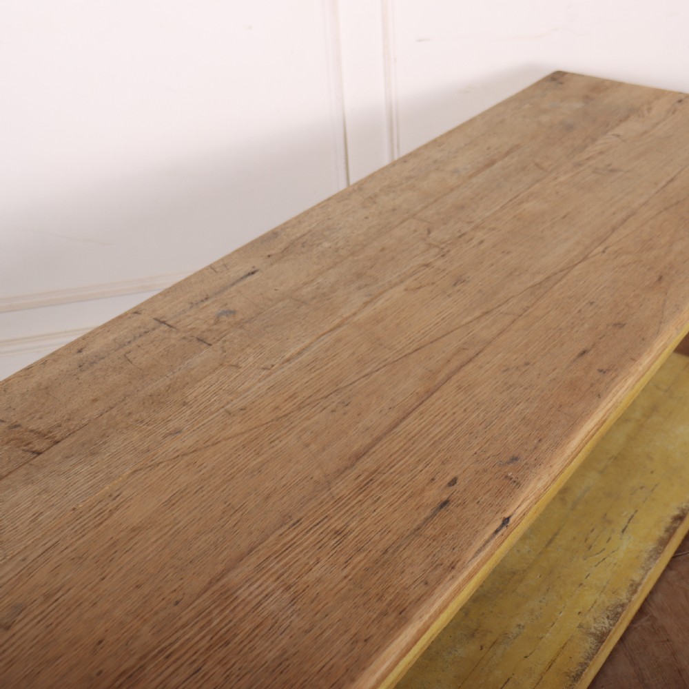 A long French drapers table featuring a natural wood plank top, a yellow painted apron and turned legs, and a low potboard shelf. View VIII