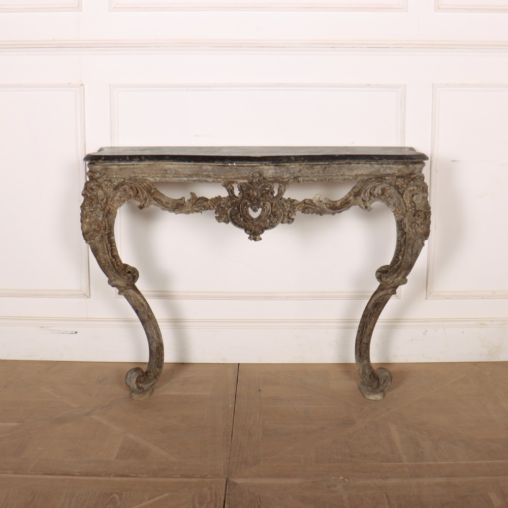 An Italian Rococo styled console table featuring heavily carved cabriole legs, a central apron cartouche motif, distressed grey paint finish, and a dark top.