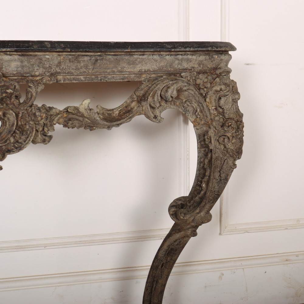 An Italian Rococo styled console table featuring heavily carved cabriole legs, a central apron cartouche motif, distressed grey paint finish, and a dark top. View III