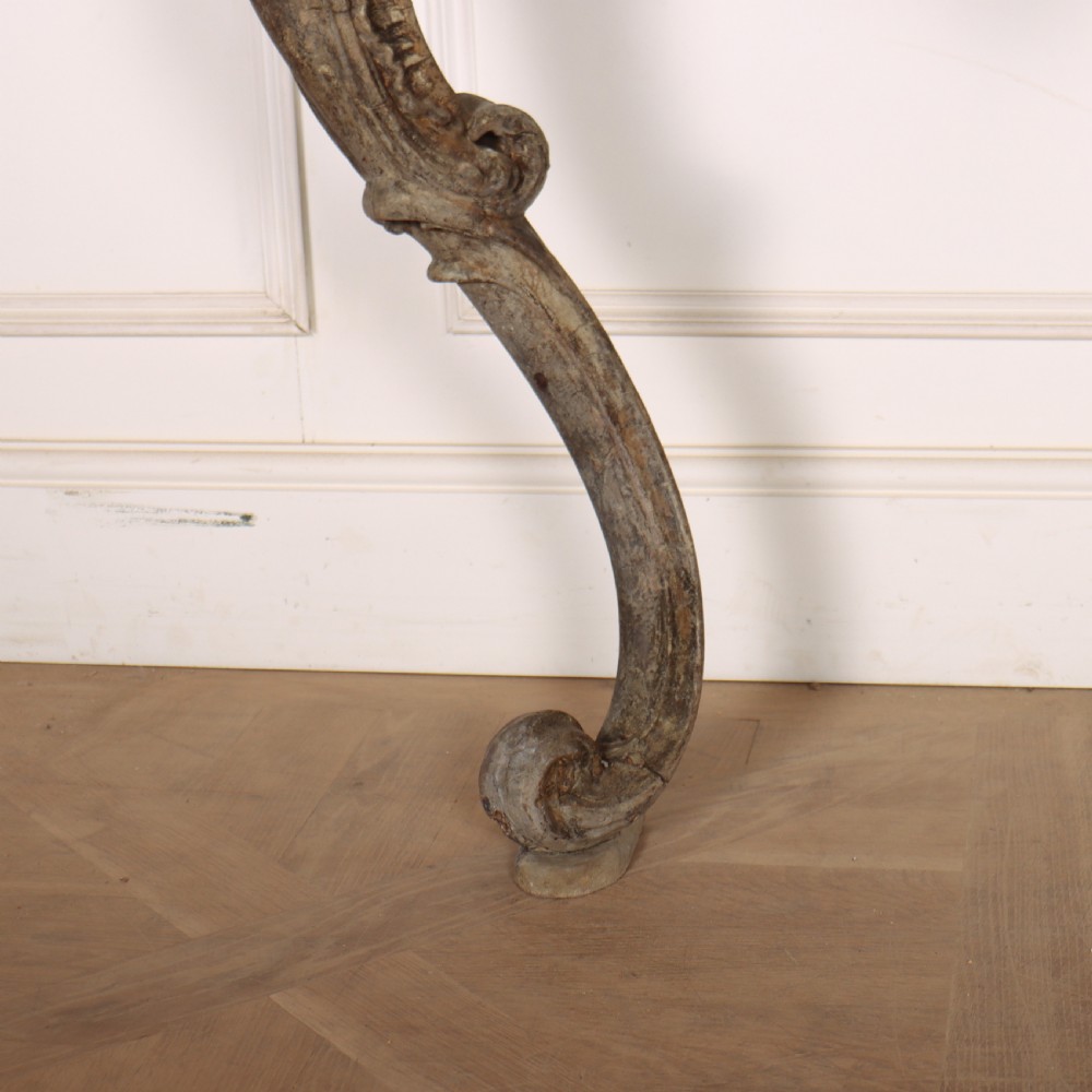 An Italian Rococo styled console table featuring heavily carved cabriole legs, a central apron cartouche motif, distressed grey paint finish, and a dark top. View V