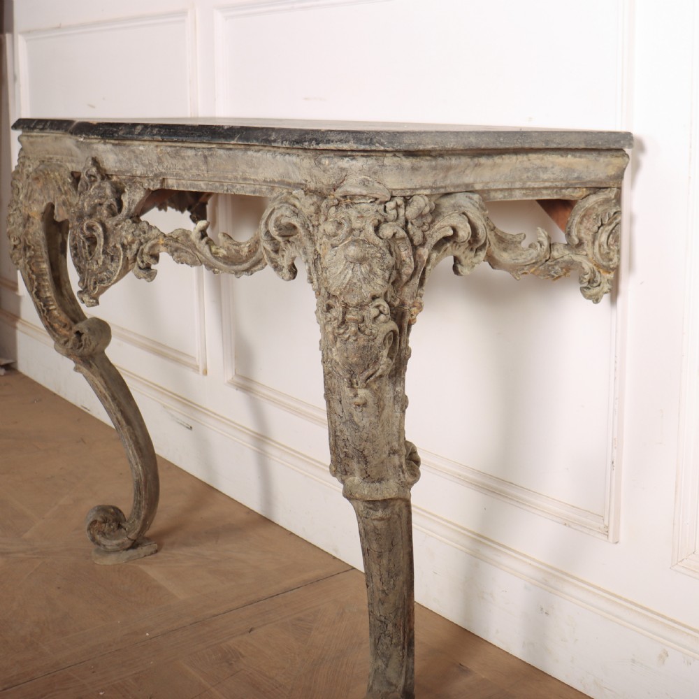 An Italian Rococo styled console table featuring heavily carved cabriole legs, a central apron cartouche motif, distressed grey paint finish, and a dark top. View VII