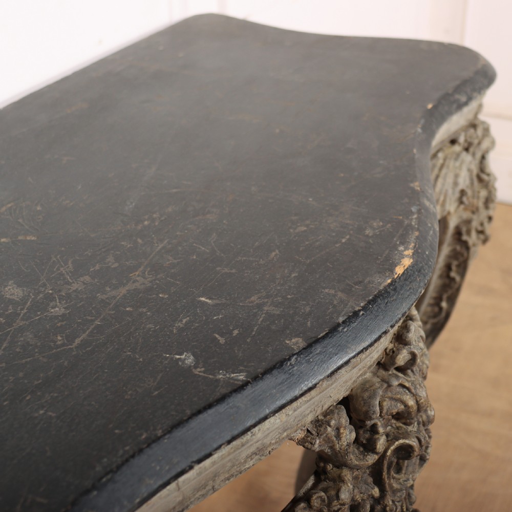 An Italian Rococo styled console table featuring heavily carved cabriole legs, a central apron cartouche motif, distressed grey paint finish, and a dark top. View X