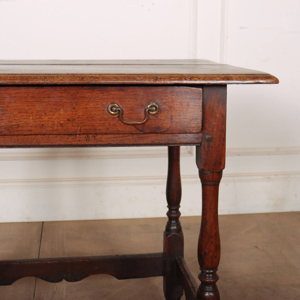 An antique English oak lamp table featuring a single drawer with brass handles, turned legs, and lower stretchers. View III