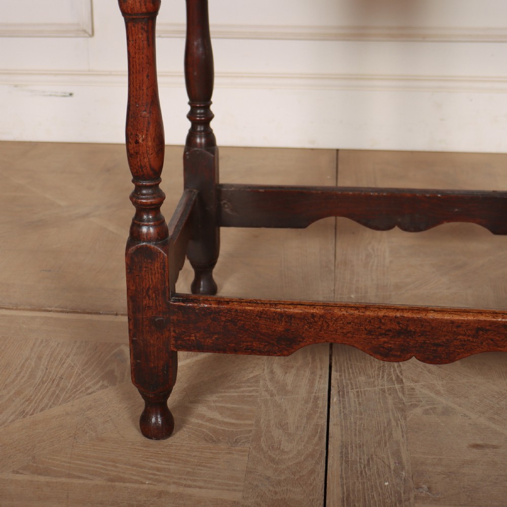 An antique English oak lamp table featuring a single drawer with brass handles, turned legs, and lower stretchers. View V
