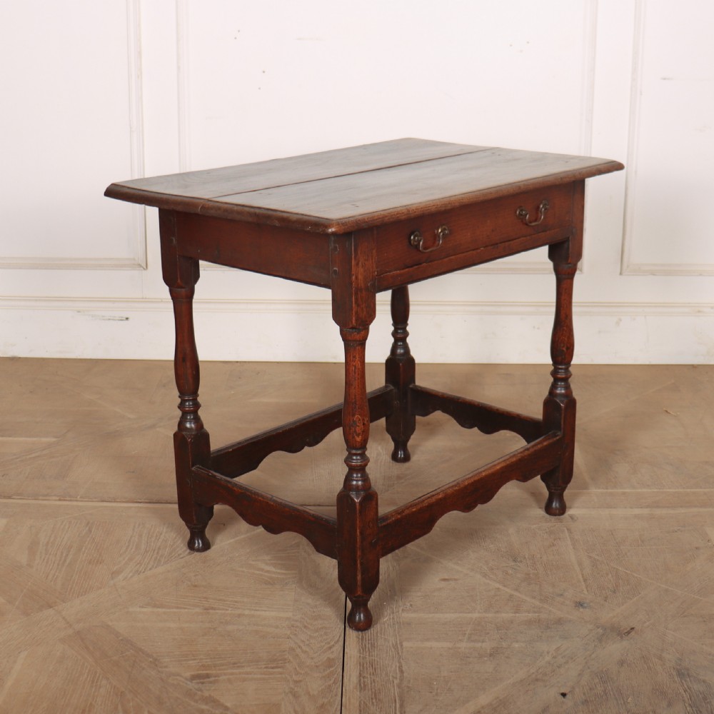 An antique English oak lamp table featuring a single drawer with brass handles, turned legs, and lower stretchers. View VI
