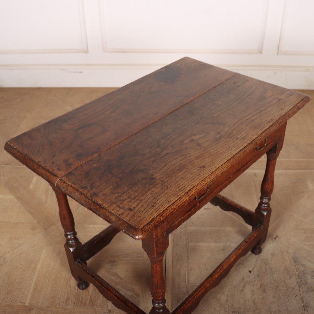 An antique English oak lamp table featuring a single drawer with brass handles, turned legs, and lower stretchers. View VII
