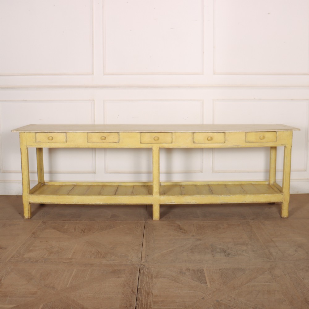 A long antique English painted wooden serving table featuring five drawers, a natural timber top, a distressed yellow base, and a low potboard shelf. View III