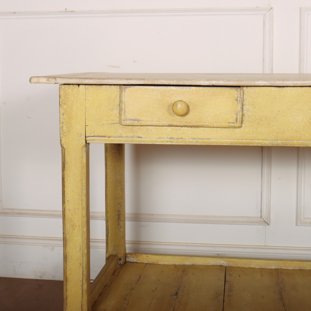 A long antique English painted wooden serving table featuring five drawers, a natural timber top, a distressed yellow base, and a low potboard shelf. View IV