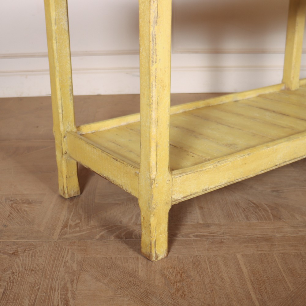 A long antique English painted wooden serving table featuring five drawers, a natural timber top, a distressed yellow base, and a low potboard shelf. View V