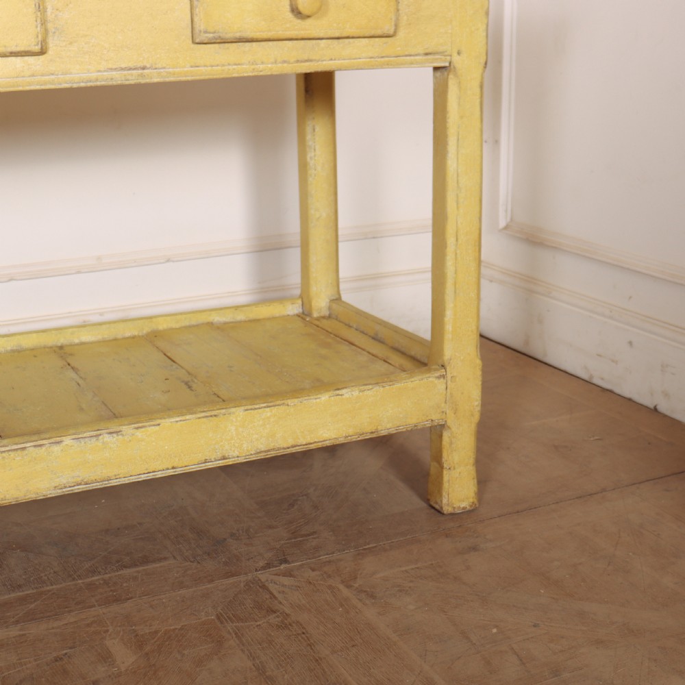 A long antique English painted wooden serving table featuring five drawers, a natural timber top, a distressed yellow base, and a low potboard shelf. View X