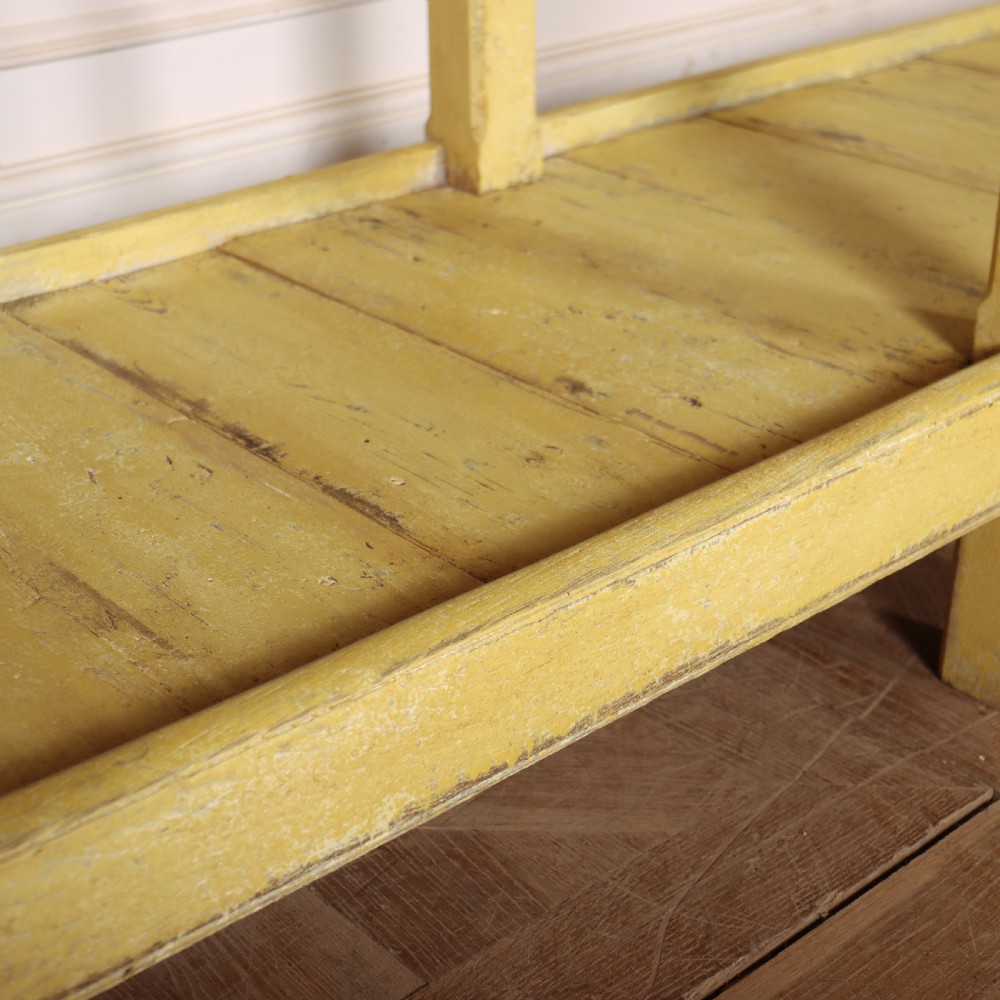 A long antique English painted wooden serving table featuring five drawers, a natural timber top, a distressed yellow base, and a low potboard shelf. View XI