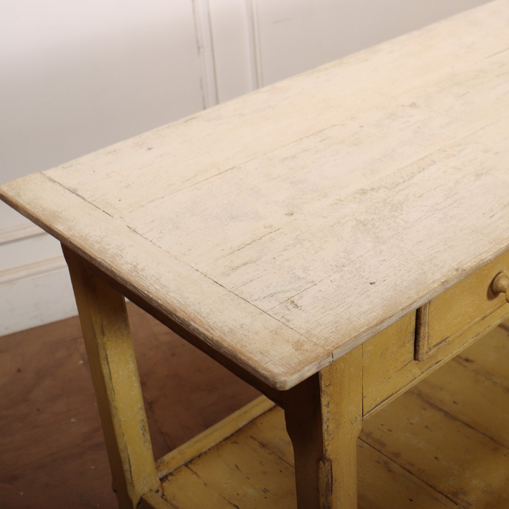 A long antique English painted wooden serving table featuring five drawers, a natural timber top, a distressed yellow base, and a low potboard shelf. View XVI