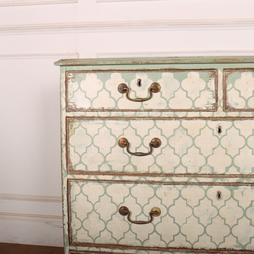 A two-over-three antique English chest of drawers painted in sage green with off-white quatrefoil patterned drawer fronts and brass handles. View II