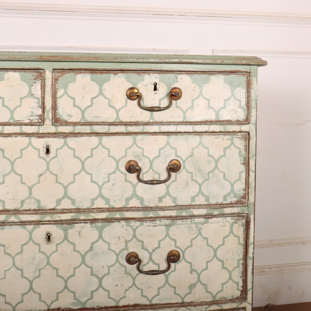 A two-over-three antique English chest of drawers painted in sage green with off-white quatrefoil patterned drawer fronts and brass handles. View III