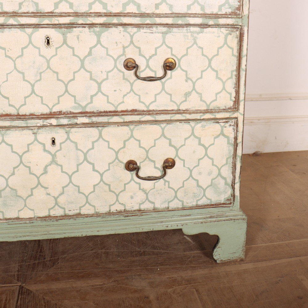 A two-over-three antique English chest of drawers painted in sage green with off-white quatrefoil patterned drawer fronts and brass handles. View V