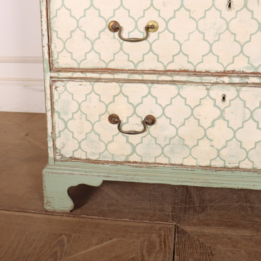 A two-over-three antique English chest of drawers painted in sage green with off-white quatrefoil patterned drawer fronts and brass handles. View VI