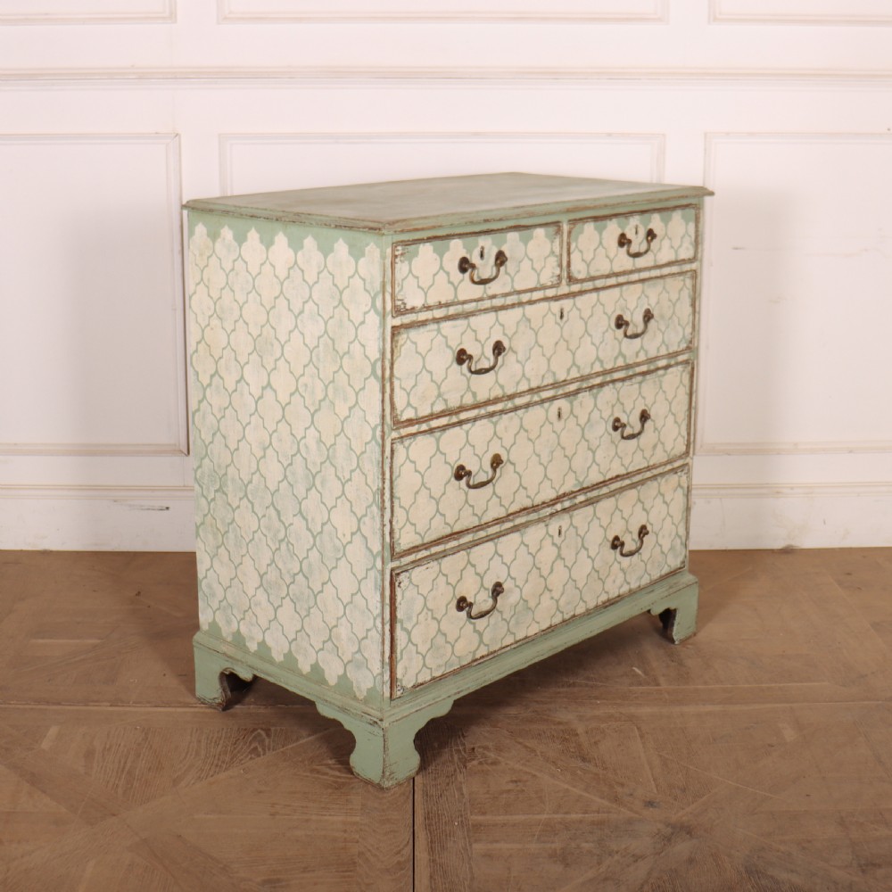 A two-over-three antique English chest of drawers painted in sage green with off-white quatrefoil patterned drawer fronts and brass handles. View VII
