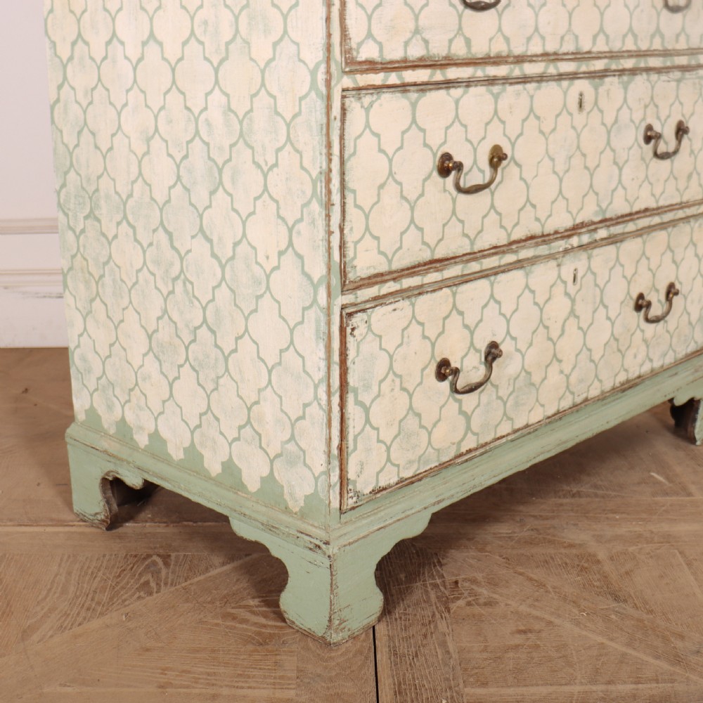 A two-over-three antique English chest of drawers painted in sage green with off-white quatrefoil patterned drawer fronts and brass handles. View VIII