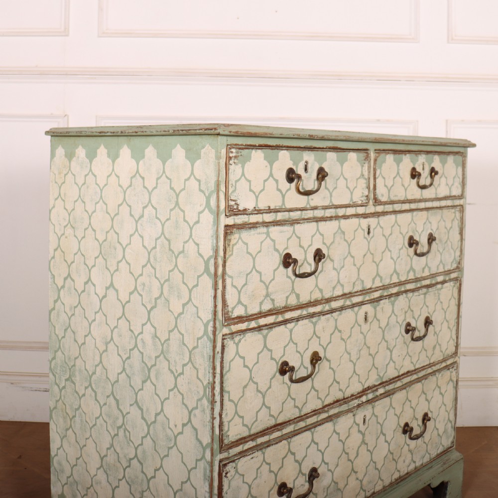 A two-over-three antique English chest of drawers painted in sage green with off-white quatrefoil patterned drawer fronts and brass handles. View IX