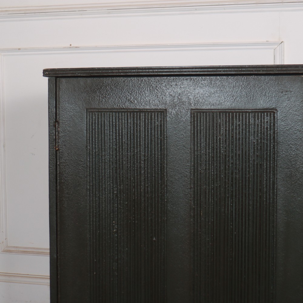 A long, narrow dark green painted wooden enfilade featuring four doors with vertical fluted panel detailing and small brass turn handles. View III