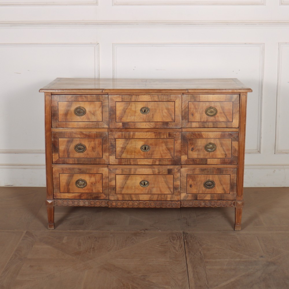 An antique Austrian walnut breakfront commode with three central drawers flanked by panels, decorated with geometric veneers and oval brass handles.