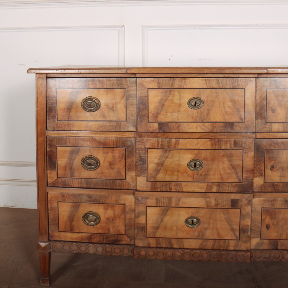 An antique Austrian walnut breakfront commode with three central drawers flanked by panels, decorated with geometric veneers and oval brass handles. View II