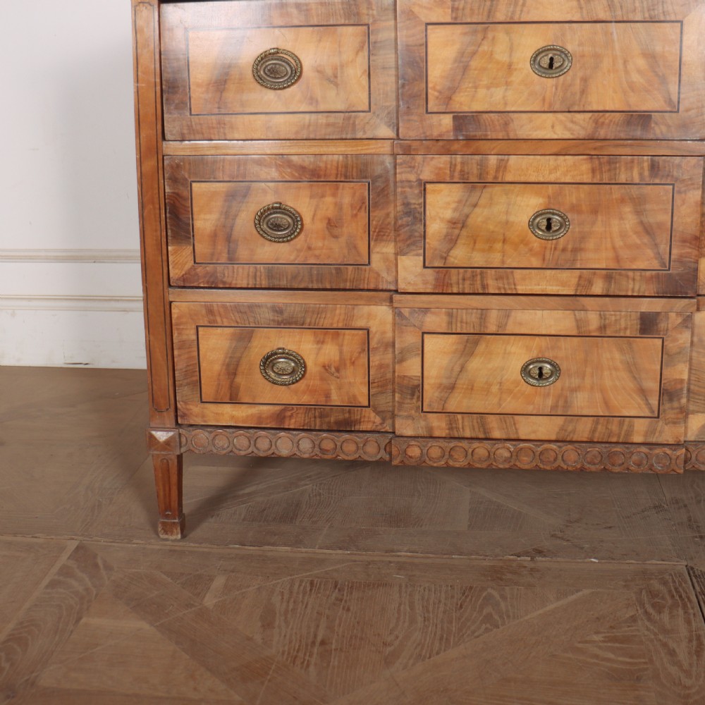 An antique Austrian walnut breakfront commode with three central drawers flanked by panels, decorated with geometric veneers and oval brass handles. View III