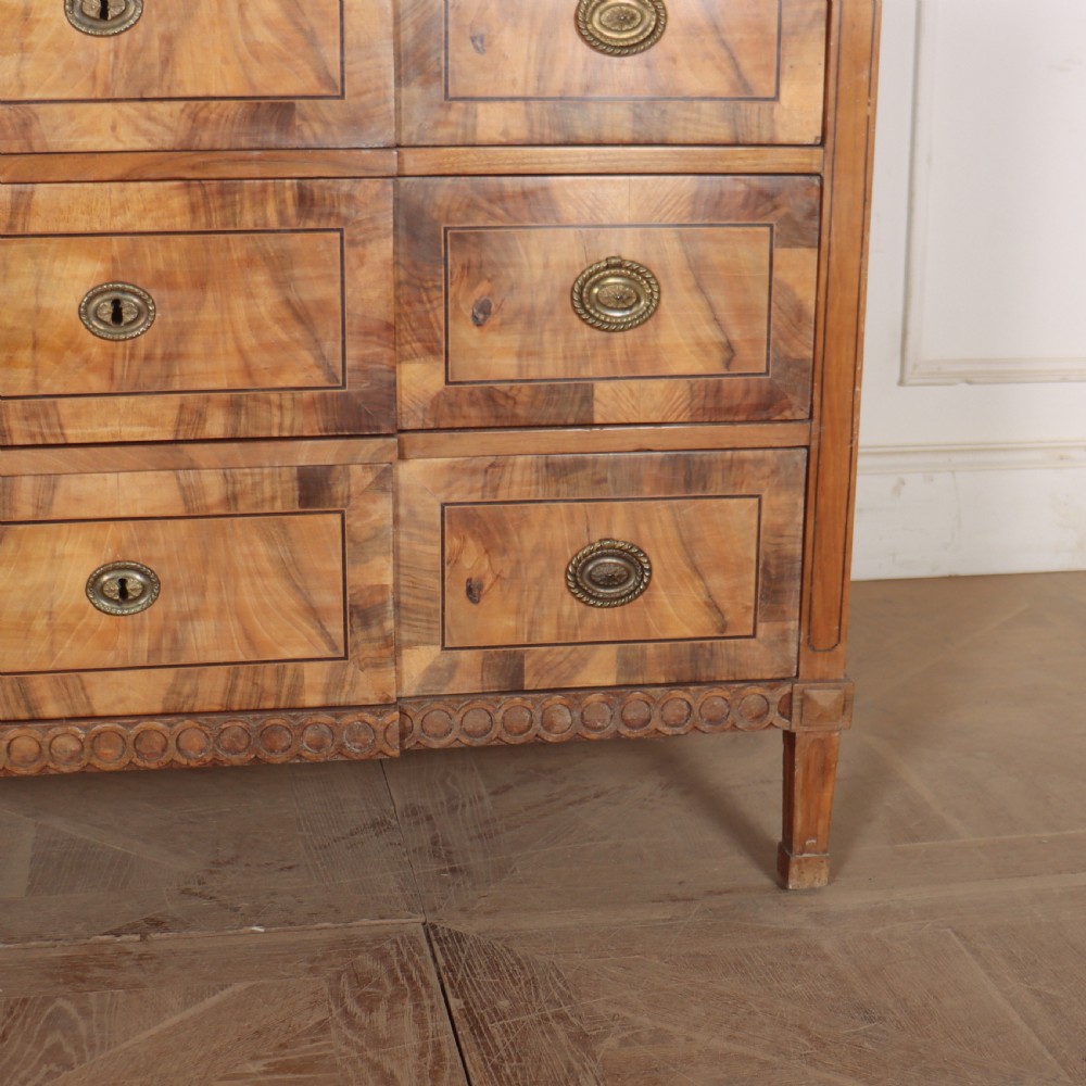 An antique Austrian walnut breakfront commode with three central drawers flanked by panels, decorated with geometric veneers and oval brass handles. View VI