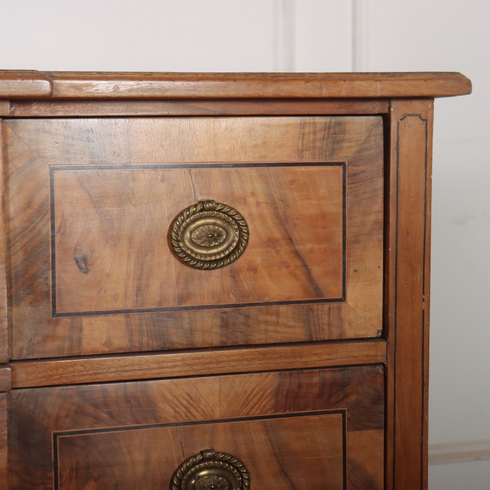 An antique Austrian walnut breakfront commode with three central drawers flanked by panels, decorated with geometric veneers and oval brass handles. View VII