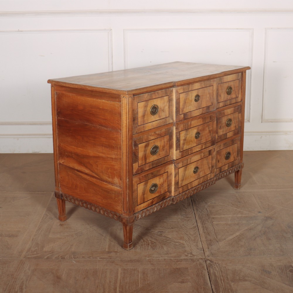 An antique Austrian walnut breakfront commode with three central drawers flanked by panels, decorated with geometric veneers and oval brass handles. View VIII