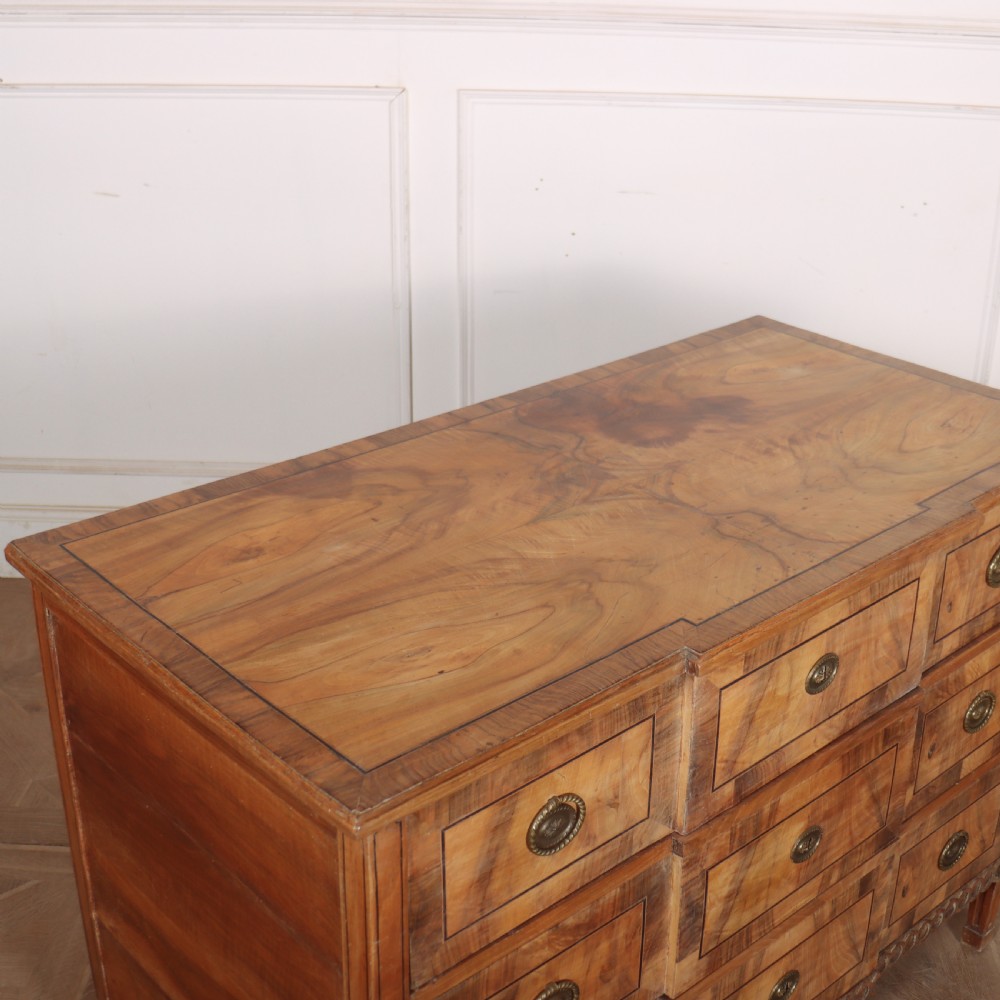 An antique Austrian walnut breakfront commode with three central drawers flanked by panels, decorated with geometric veneers and oval brass handles. View X