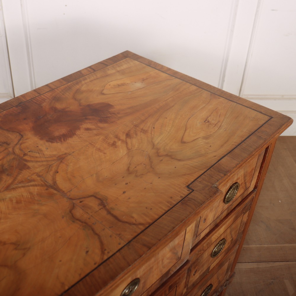 An antique Austrian walnut breakfront commode with three central drawers flanked by panels, decorated with geometric veneers and oval brass handles. View XII
