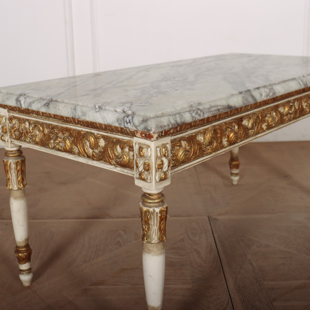 A rectangular French Louis XVI style low coffee table featuring a grey and white veined marble top set on a carved giltwood and painted frame with fluted tapered legs. View II