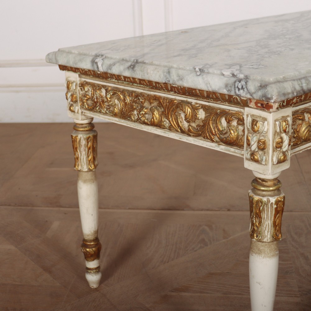 A rectangular French Louis XVI style low coffee table featuring a grey and white veined marble top set on a carved giltwood and painted frame with fluted tapered legs. View III