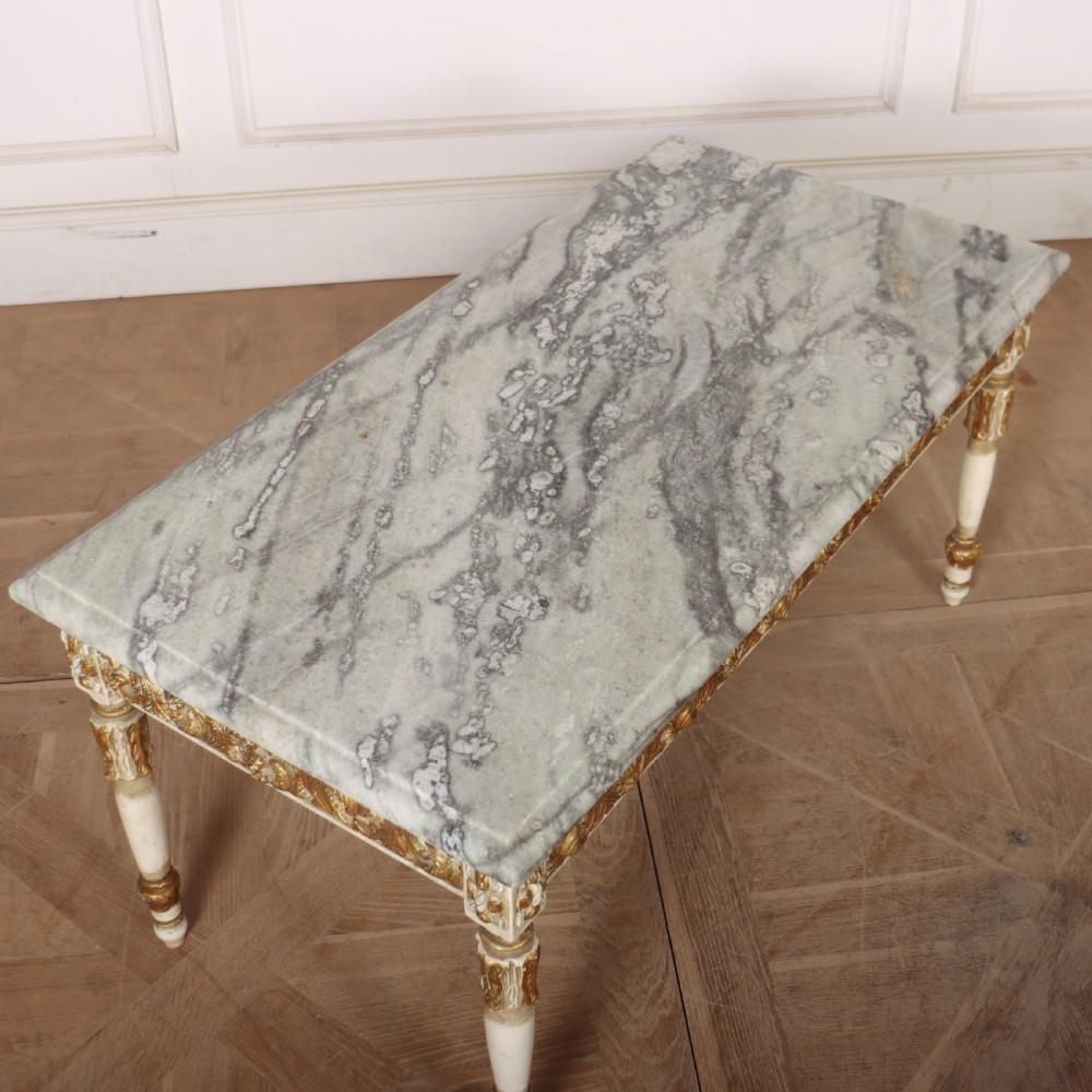 A rectangular French Louis XVI style low coffee table featuring a grey and white veined marble top set on a carved giltwood and painted frame with fluted tapered legs. View V