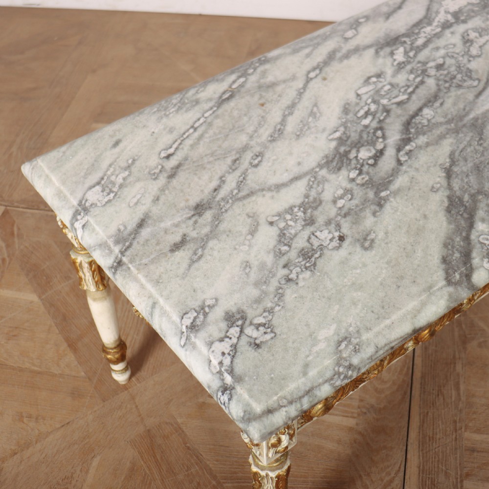 A rectangular French Louis XVI style low coffee table featuring a grey and white veined marble top set on a carved giltwood and painted frame with fluted tapered legs. View VI